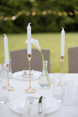 Elegant outdoor dining setup with fine tableware and soft candlelight under twinkling lights