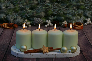 Adventsdekoration für den vierten Advent : Dekoration mit mintgrünen  Adventskerzen vor einer weihnachtlichen Kulisse mit Platz für Text.