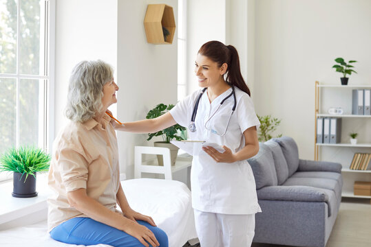 Friendly female doctor comforting elderly patient sitting on couch in hospital. Warm and caring physician or cardiologist providing support to senior woman, cheering her up during medical checkup.