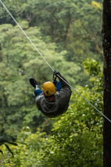Person ziplining through tropical forest on a rainy day