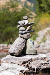 Cairn of stones balanced on the river in sunny day