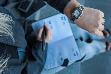 Woman writing in a notebook while wearing a watch