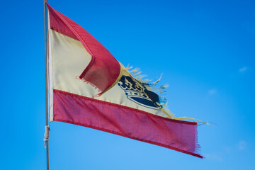 A torn and weathered Spanish flag symbolizing political unrest, economic crisis, national struggles. Old flag of Spain on sailng boat.