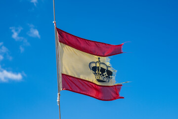 A torn and weathered Spanish flag symbolizing political unrest, economic crisis, national struggles. Old flag of Spain on sailng boat.