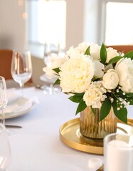 Elegant white peony centerpiece on a gold tray on a white tablecloth