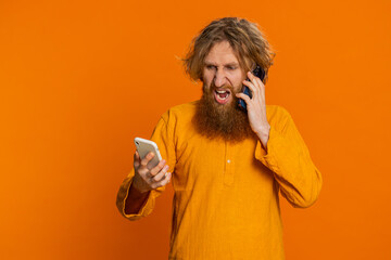 Irritated nervous stressed Caucasian man talking screaming on two mobile phones having conversation...