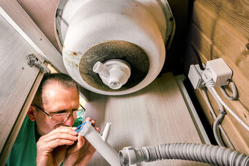 Bottle trap under kitchen sink in process of installation, plumber prepares outlet pipe with...