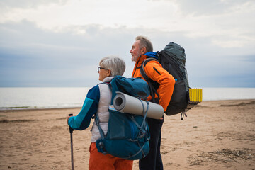 Hiking tourism adventure. Senior couple man woman enjoying outdoor recreation hiking on beach. Happy old people backpackers hikers enjoy walking hike trekking tourism active vacation beauty of nature