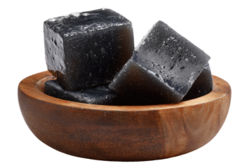 Dark gray, cube-shaped candies in a wooden bowl