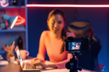 Smiling creative young beautiful Asian influencer recording on camera with positive podcast speech...