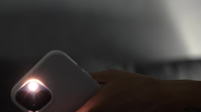 A man in the dark with his phone's flashlight on.
Close-up of using a smartphone's flashlight.
Phone backlight.
Light, smartphone, darkness.