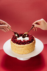 Romantic dessert moment with two spoons and berry cake on red background