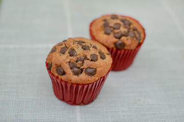 Imagen a detalle de dos cupcakes de vainilla con chispas de chocolate en una mesa color gris