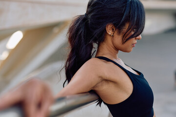 Fit woman stretching her arms on a railing during an intense fitness workout, showcasing strength...