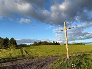 Uma cruz em um cruzamento no meio de um campo de trigo verde