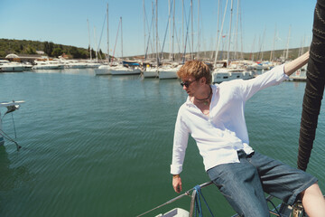A man confidently standing on the deck of a luxury yacht overlooking the water