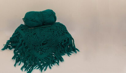 Crocheted item in green merino wool yarn with crochet hook on neutral background, flat lay with copy space for crochet tutorials and craft inspiration