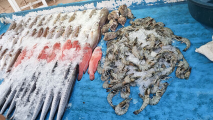 Fresh seafood display featuring various fish, shrimp and shellfish on ice with garnishes. Ideal for culinary enthusiasts and seafood lovers.