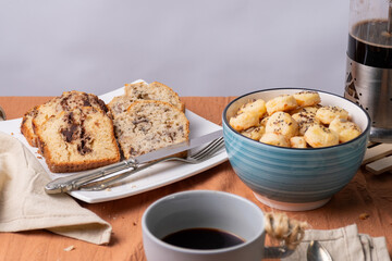 Coffee, banana bread, chocolate bread, and cheese crackers with seeds.