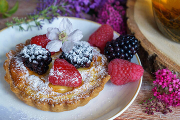 Tarts topped with fresh berries and dusted with powdered sugar. 