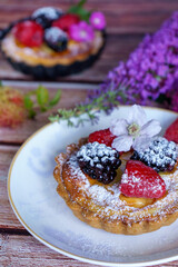 Tarts topped with fresh berries and dusted with powdered sugar. 