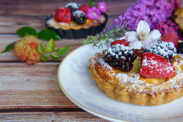 Tarts topped with fresh berries and dusted with powdered sugar. 