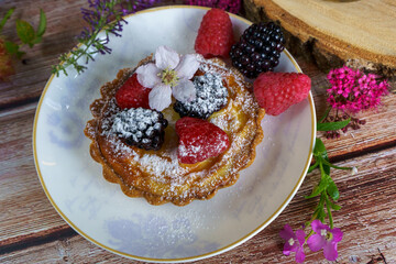 Tarts topped with fresh berries and dusted with powdered sugar. 