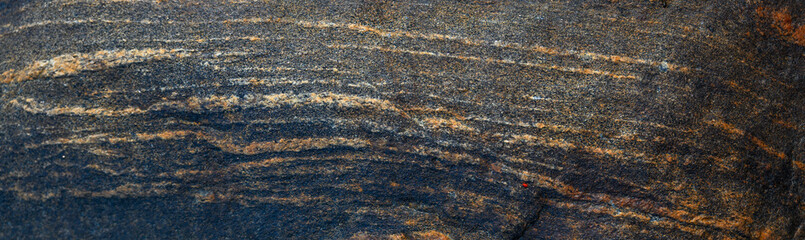 Closeup of natures art, black gray rock with orange and white mineral stripes, as a nature background
