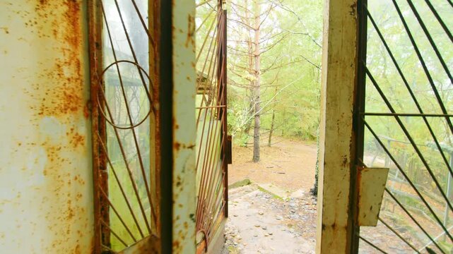 An evocative interior view of the decaying entrance to the famous Cafe Pripyat, once a vibrant hub near the river port in the ghost city of Pripyat, Ukraine. Overgrown with vegetation, the broken wind