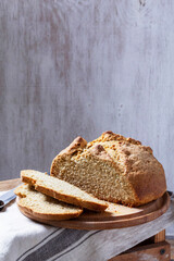 Homemade Irish soda bread cut into pieces and knife on wooden background.