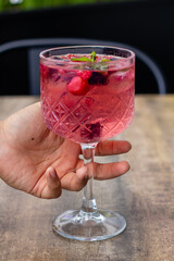 Copa de alcohol con frutos sostenida por una mano