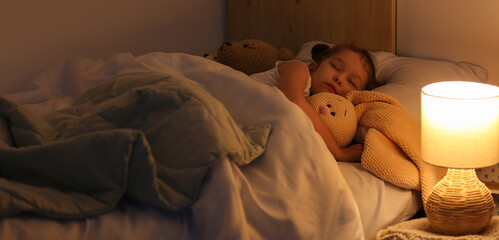 Cute little girl with knitted toy bunny sleeping in bedroom at night © Pixel-Shot