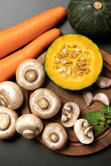 Fresh vegetables and fruits with pumpkin carrot apple and mushrooms on dark background