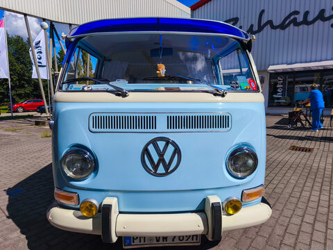 Havel, Germany - September 07, 2025: Vintage Volkswagen bus in pastel blue color parked outside a modern building, showcasing its iconic design and nostalgic charm in a vibrant setting