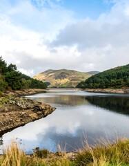 Fototapeta premium Tranquil lake reflecting hills and clouds