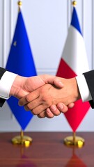 Two businessmen shake hands, EU and French flags behind them