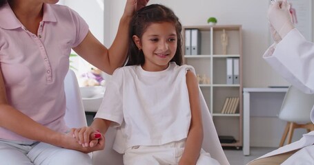 Doctor gives an injection to a child as a mother holds her hand, supporting vaccination and immunization in a healthcare setting for protection and smile. Child gets vaccine shot in medical clinic. - Powered by Adobe