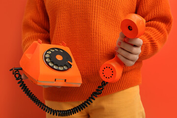 Woman holding retro telephone on orange background, closeup