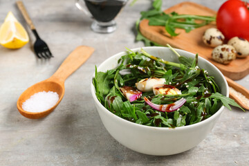 Bowl with healthy arugula salad on grey grunge background, closeup