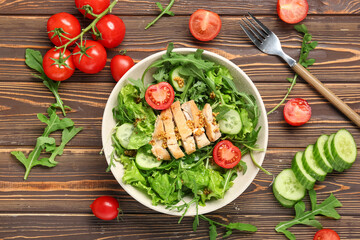 Composition with bowl of healthy arugula salad and ingredients on wooden background