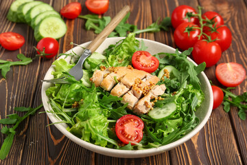 Composition with bowl of healthy arugula salad and ingredients on wooden background, closeup