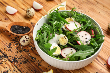 Bowl with healthy arugula salad on wooden background, closeup