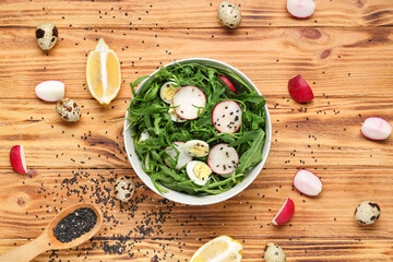 Bowl with healthy arugula salad on wooden background