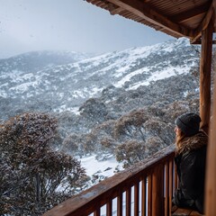Woman Looking at Snowy Mountains From Wooden Cabin Balcony in Winter