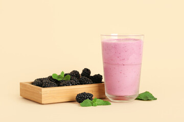 Glass of fresh blackberry smoothie and wooden box with berries on yellow background
