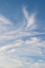 Sunset sky background, blue sky with hint of yellow and white wispy clouds
