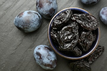 Dried prunes and fresh plums on black table, flat lay