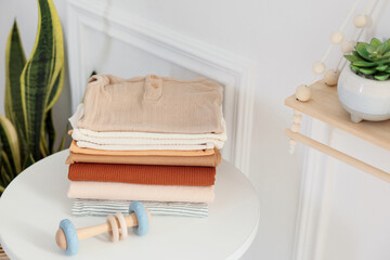Stack of clean baby clothes and toy on white table indoors, space for text