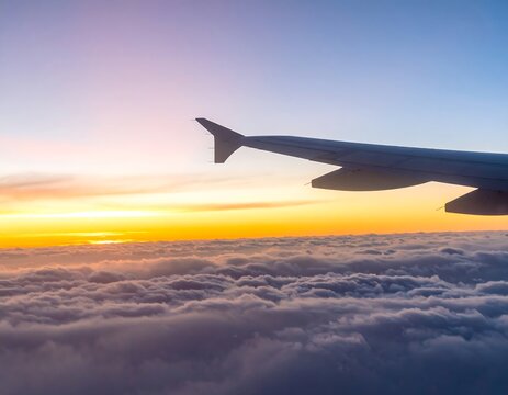 Airplane wing over colorful clouds at sunrise