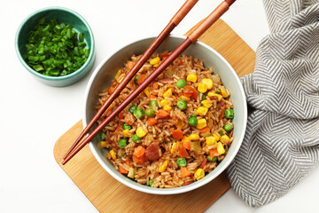 Tasty fried rice in bowl on white table, flat lay